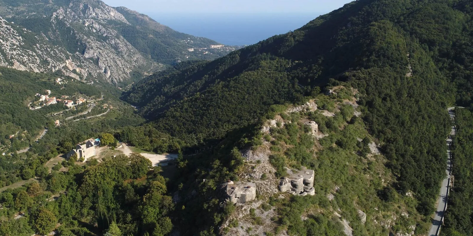 Aerial view of the Route des Grandes Alpes, a winding mountain road with alpine peaks in the background